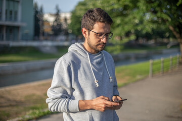 Man on smartphone in park, back light