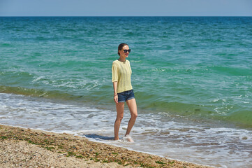 A young thin woman walks on the seashore