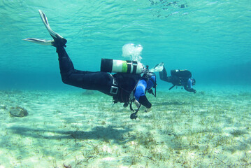 Diving instructor and student in underwater exercise. Instructor teaches student to dive....