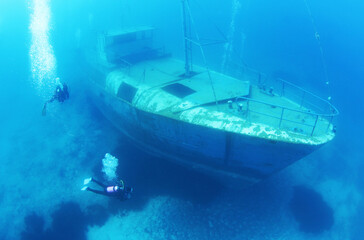 Scuba Divers Exploring underwater ship wreck 