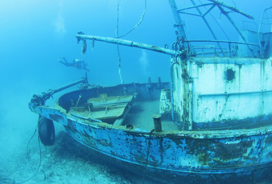 Scuba Divers Exploring underwater ship wreck 