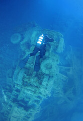 A scuba diver floats over the wreckage of a truck that was part of the cargo of the sunken ship...