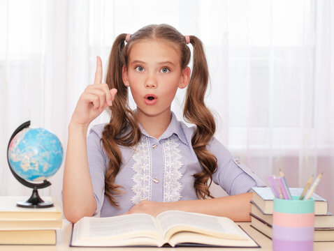 Education and school concept. Child is sitting at the desk with finger up and say Ooo.
