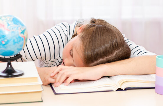 Back to school. Tired little child girl sleeping on the desk while doing homework