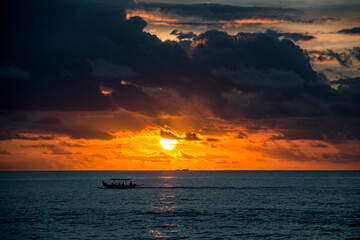 Fototapeta na wymiar Boat in the ocean at sunset and bright sky