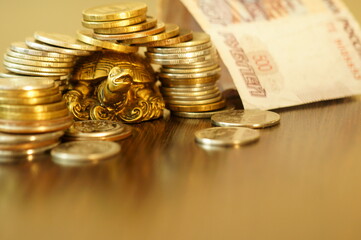 Metal turtle with coins on a gold background. The coins are arranged in the form of a turtle house.