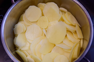 Thinly sliced fresh peeled potatoes in a bowl