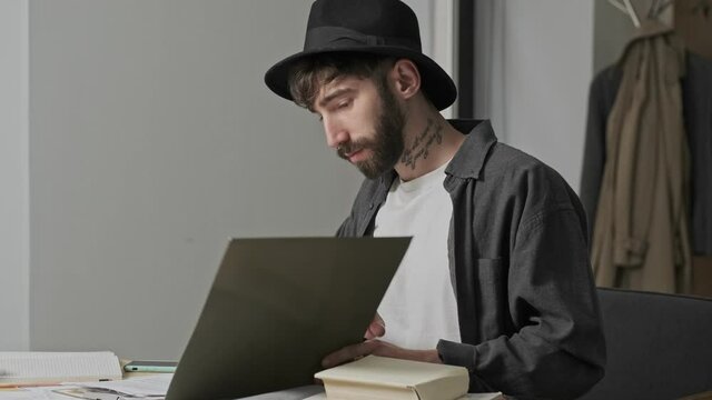 A charming stylish young artist man creator is working with papers and folders sitting in the office