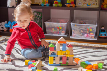 Cute child having fun playing with colorful wooden blocks, at home.