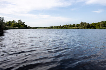 beautiful lake with small waves on the background of sky with clouds. A typical pond in the countryside