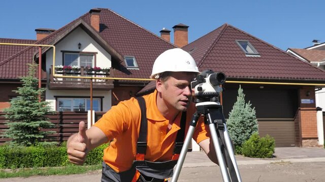 Professional Engineer Surveyor Takes Measures with Leveling Instrument on Construction Site