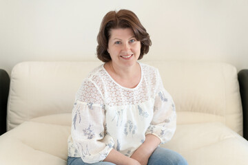 Naklejka premium Middle aged woman sitting on sofa in a room
