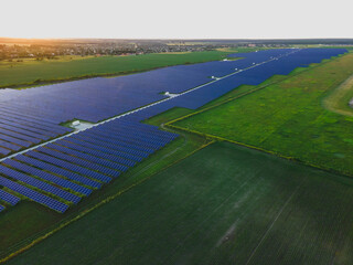 Aerial drone view into large solar panels at a solar farm at bright sunset. Solar cell power plants.