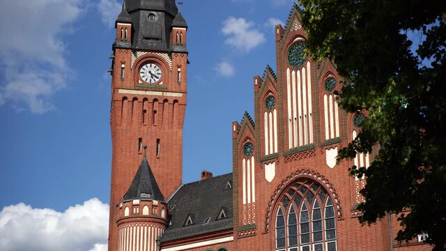 District Koepenick in Berlin, Germany close up view of birds flying into old town city hall clock tower historical building sunny summer day moving clouds in background 4K 25p shutter speed 1/50