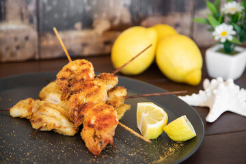 Grilled squid skewers in a black plate resting on rustic wooden background