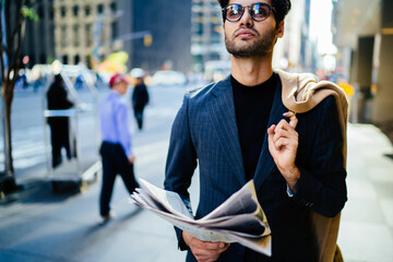 Cropped image of proud seo in formal suit walking on Manhattan avenue with newspaper, handsome...
