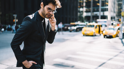 Stressed businessman having mobile phone conversation standing on street in downtown, angry male...