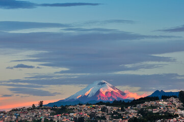 The last rays of sun fall on the city of Quito with the Cotopaxi Volcano in the background