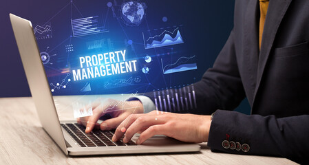 Businessman working on laptop with PROPERTY MANAGEMENT inscription, new business concept