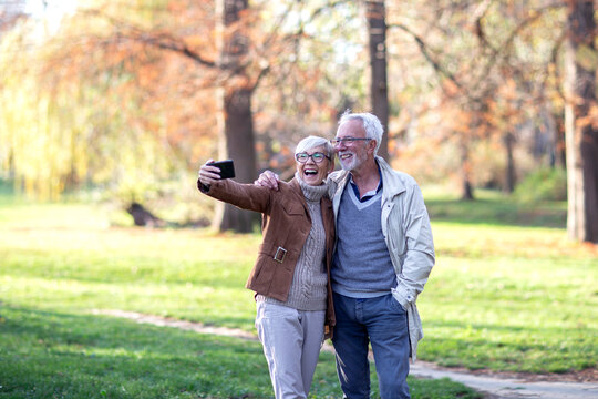 Mature couple taking selfie by mobile phone in public park