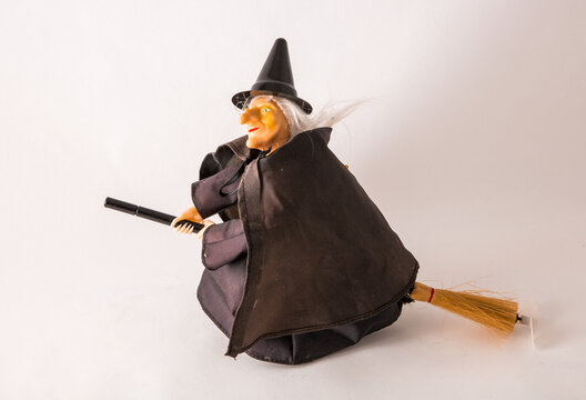 a witch figurine with a broom on an isolated white background.