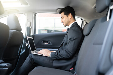 Fototapeta na wymiar Young Businessman Using Laptop In Taxi