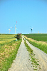 Fototapeta na wymiar Straße mit Windkraftanlage / Windrädern und Feldern in Niederösterreich