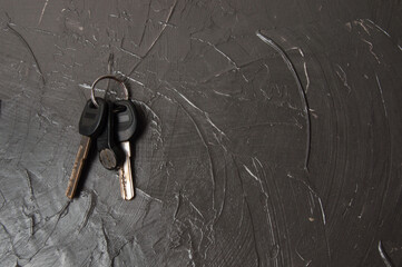 Keys to the house or flat on a dark gray concrete background with copy space, view from the top. Home purchase concept