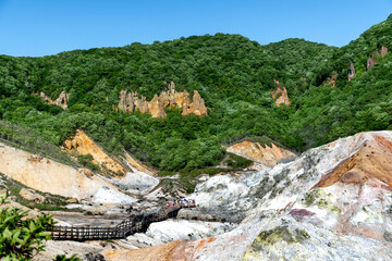 Jigokudani hell valley walking trail in Noboribetsu, Hokkaido, Japan. Selective focus at front banister of wooden footpath.