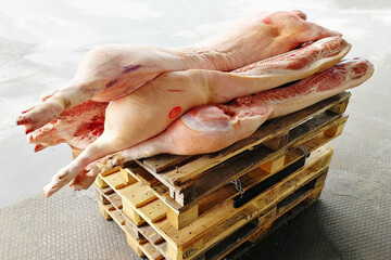 Pork half-carcasses on scales. Raised with wooden pallets