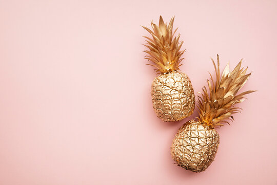 Gold tropical pineapple on a pastel pink background. Flat lay summer background
