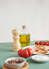 tomato wooden pepper mill and olive oil bottle on a green table