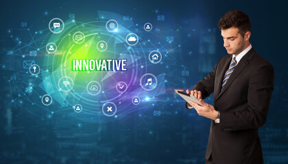 Businessman thinking in front of technology related icons and INNOVATIVE inscription, modern technology concept