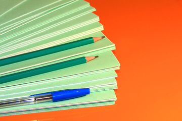 A stack of school green notebooks on a bright background.