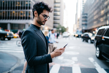 Pensive executive manager reading incoming notification with money balance on account received on smartphone crossing New York street.Prosperous entrepreneur in formal wear checking mail on telephone - Powered by Adobe