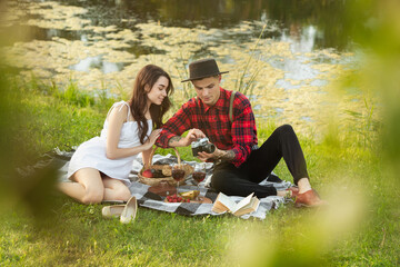 Talking. Caucasian young, happy couple enjoying weekend together in the park on summer day. Look lovely, happy, cheerful. Concept of love, relationship, wellness, lifestyle. Sincere emotions.