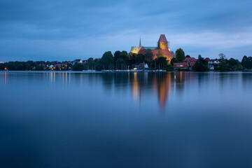 Fototapeta na wymiar Ratzeburg Dome peninsula in golden light at blue hour evening with reflection in the water, Schleswig-Holstein, Germany