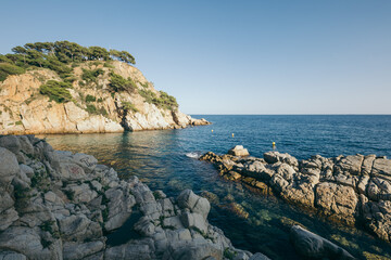 A rocky cliff with water and a mountain in the background