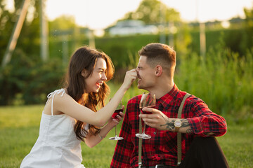 Fototapeta premium Laughting, having fun. Caucasian young couple enjoying weekend together in the park on summer day. Look lovely, happy, cheerful. Concept of love, relationship, wellness, lifestyle. Sincere emotions.