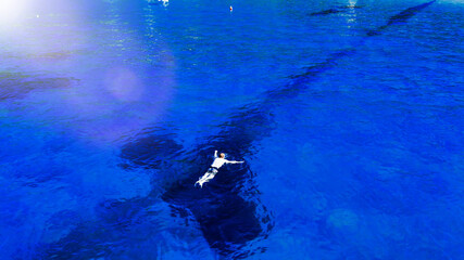 Aerial view of swimmer swimming in the crystal clear ocean