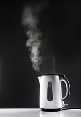 Hot electric white kettle on table on grey background