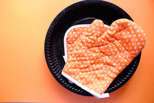 Kitchen Gloves On Orange Background Top Down.