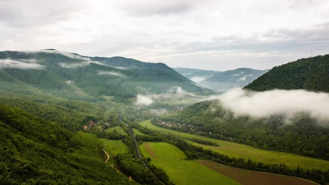 Time lapse from the top of the mountain overlooking the fogy and cloudy valley. Captured at dawn. With beautiful vapor after wet night. 
