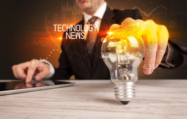 Businessman holding lightbulb with TECHNOLOGY NEWS inscription, Business technology concept