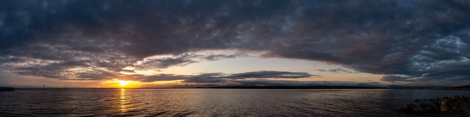 Obraz premium White Rock, Greater Vancouver, British Columbia, Canada. Beautiful Panoramic View of a cloudy and colorful sunset over the Pacific Ocean Coast. Nature Background Panorama