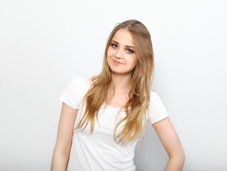 Pretty smiling young woman with fair blond long hair in casual dress, blue jeans and t-shirt. Studio shot of good looking beautiful woman isolated against grey studio wall