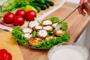 Fried zucchini. The process of making fried zucchini. Woman puts creamy garlic sauce on fried zucchini. Vegetarian cuisine.