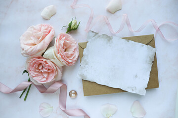 Obraz na płótnie Canvas vintage background with roses and paper. postcard mockup. a small bouquet of pink roses and an envelope. wedding invitation. greeting card