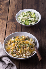 Traditional Middle Eastern dish, Mujadara of lentils, rice and fried onions with a salad of cabbage and cucumbers on wooden table, top view, selective focus, space	
