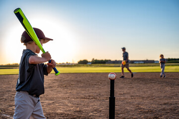 Caucasian boy with baseball bat at home plate ready to hit a ball off a tee